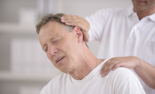 A man with osteochondrosis of the neck waiting for a manual massager